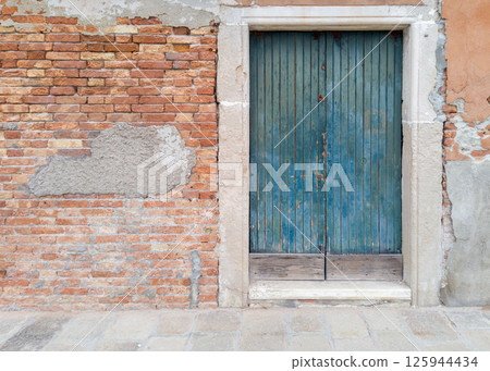 Old blue wooden door in brick wall 125944434