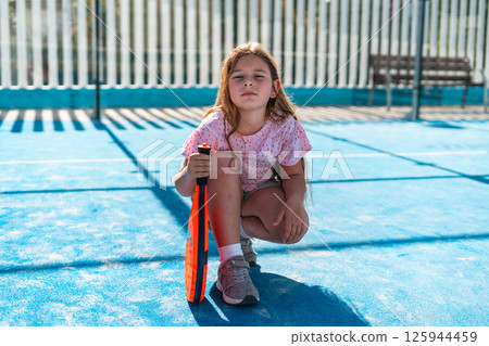 Young girl confidently posing on the tennis court with racket. 125944459