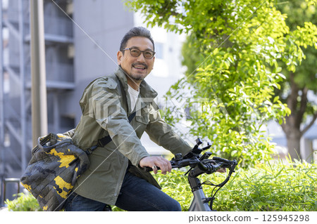 Smiling man in his late 50s riding a bicycle 125945298