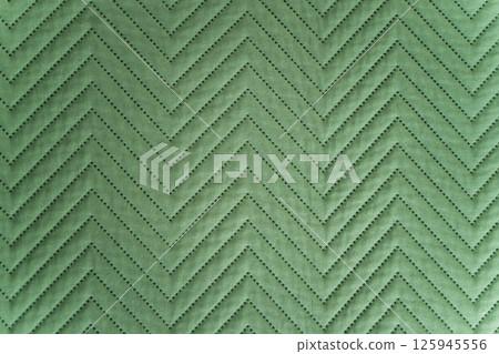 Close-up of quilted green fabric with zigzag stitched pattern in soft lighting 125945556