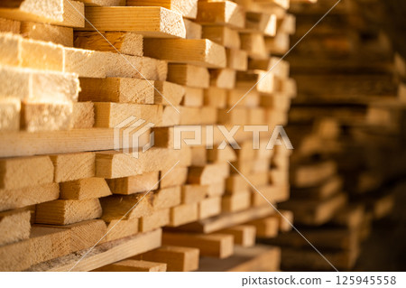 Selective focus on stacked wood planks in warehouse with blurred background 125945558