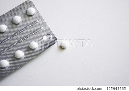 Single tablet near silver blister pack on white background 125945565