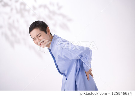 Middle-aged woman grimacing from back pain Middle-aged woman grimacing from back pain 125946684