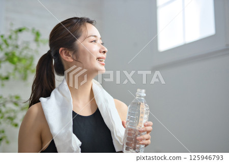 A woman in her twenties drinking water in yoga wear 125946793