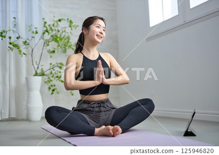 一位二十多歲的女性正在享受線上瑜伽 一位二十多歲的女性正在享受線上瑜伽 125946820