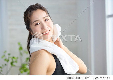 一名二十多歲的女子穿著瑜珈服，用毛巾擦汗 125946852