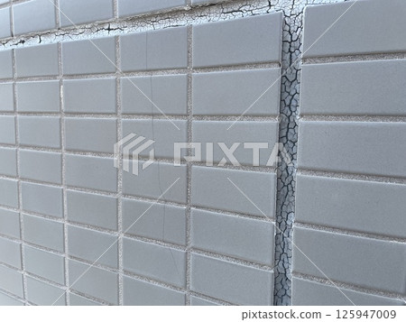 Exterior wall in need of repair due to deterioration of sealant and cracked tiles 125947009