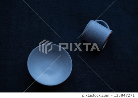 一塊靛藍染色的布上放著一個小盤子和一個牛奶罐 125947271