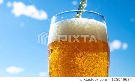 A glass to quench your thirst under the blue sky: A refreshing beer on a summer's day - A golden temptation poured into a glass A glass to quench your thirst under the blue sky: A refreshing beer on a summer's day - A golden temptation poured into a glass 125949684