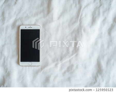 Minimalist smartphone displayed on soft white fabric for modern design concepts 125950123