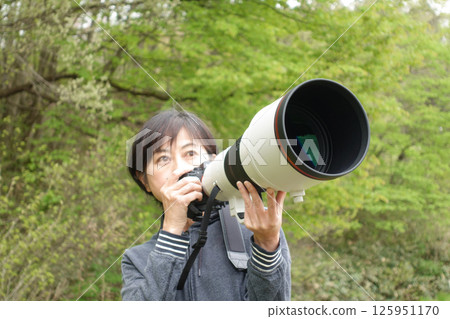 A middle-aged woman searching for wild birds with a telephoto camera A middle-aged woman searching for wild birds with a telephoto camera 125951170