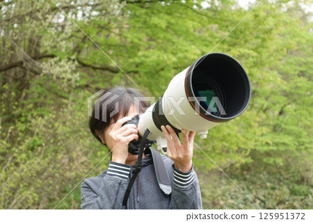Woman looking through camera, no face, photographing wild birds and animals 125951372