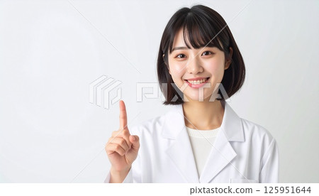 A young woman in a white coat pointing up A young woman in a white coat pointing up 125951644