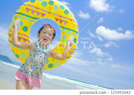 A girl playing with a swim ring in the summer sea A girl playing with a swim ring in the summer sea 125952042