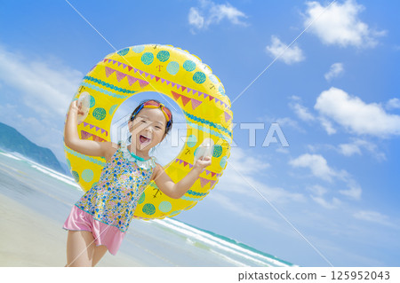 A girl playing with a swim ring in the summer sea 125952043