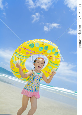 A girl playing with a swim ring in the summer sea 125952045