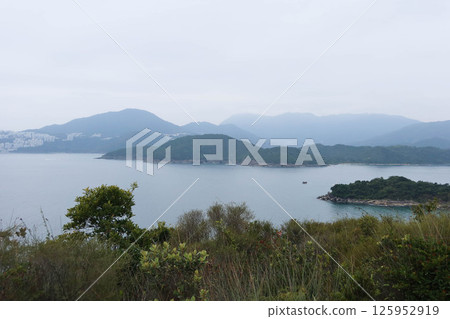 scenic mountain view of outlying islands along the sea taking from the hiking trail of Sharp Island (Kiu Tsui Chau) scenic mountain view of outlying islands along the sea taking from the hiking trail of Sharp Island (Kiu Tsui Chau) 125952919