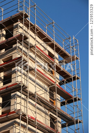 A building under construction with scaffolding on the side 125953329