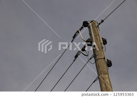 A tall power pole with wires running up it 125953363