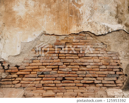 Picture of old cement wall that is cracked, chipped, and broken. 125953392