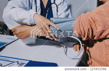 Nurse measuring blood pressure of elderly woman at table, closeup. Assisting senior generation Nurse measuring blood pressure of elderly woman at table, closeup. Assisting senior generation 125953566