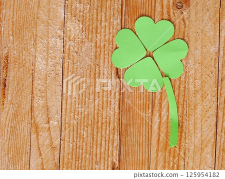 A green paper clover is placed on a wooden surface A green paper clover is placed on a wooden surface 125954182