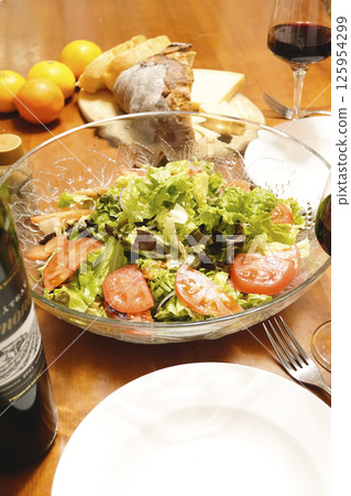 Dinner table with red wine, bread, cheese and salad Dinner table with red wine, bread, cheese and salad 125954299