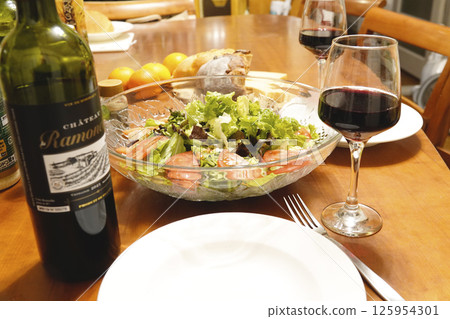 Dinner table with red wine, bread, cheese and salad Dinner table with red wine, bread, cheese and salad 125954301