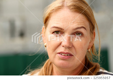 Close-up on the face of a serene Caucasian woman with blonde hair and expressive green eyes, around 40-45 years old. Candid moment Close-up on the face of a serene Caucasian woman with blonde hair and expressive green eyes, around 40-45 years old. Candid moment 125955057