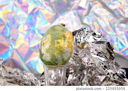 Whole bergamot ore a rotten lemon side-by-side on a shiny foil surface against a dark background. Food contrast Whole bergamot ore a rotten lemon side-by-side on a shiny foil surface against a dark background. Food contrast 125955059