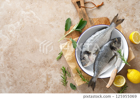 Fresh raw sea bream fish or dorado fish with lemon and herbs, top view 125955069