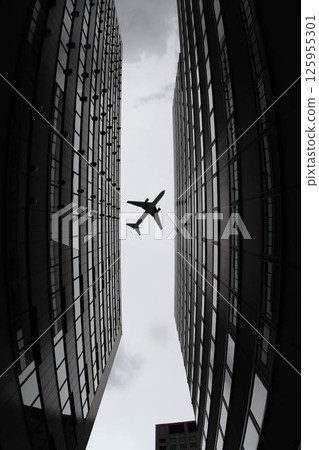 Airplane silhouette photographed between buildings, ultra-wide-angle version Airplane silhouette photographed between buildings, ultra-wide-angle version 125955301