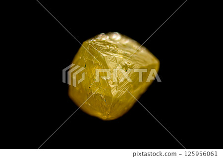 Natural rough yellow diamond crystal on dark background 125956061