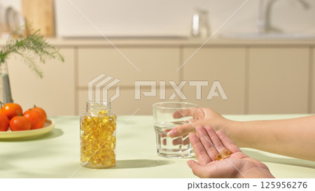 Daily medication activity as prescribed by a doctor. A medicine bottle, opened and placed on the kitchen table. Plate of fresh green vegetables and a potted indoor plant that is blurred. Copy space. 125956276