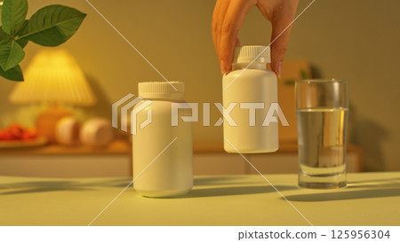 Two different sized medicine bottles were placed on the desk, the smaller one being lifted off the desk by the user. Next to it was a glass of purified water for the patient to take the medicine. 125956304