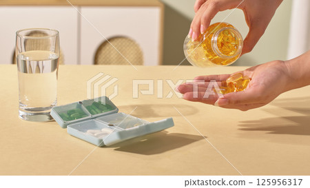 Scene of a doctor dispensing pills from a glass bottle to a medicine box. Drugs medical tablets on hand. Hand pouring capsules from medication bottles. Medicines provide vitamins and nutrients. 125956317