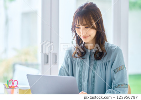Young woman operating a personal computer at home Young woman operating a personal computer at home 125956787
