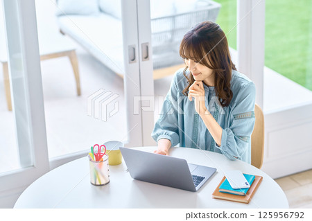 Young woman operating a personal computer at home 125956792