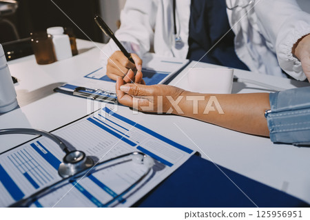 Nurse measuring blood pressure of elderly woman at table, closeup. Assisting senior generation Nurse measuring blood pressure of elderly woman at table, closeup. Assisting senior generation 125956951