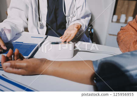 Nurse measuring blood pressure of elderly woman at table, closeup. Assisting senior generation Nurse measuring blood pressure of elderly woman at table, closeup. Assisting senior generation 125956955