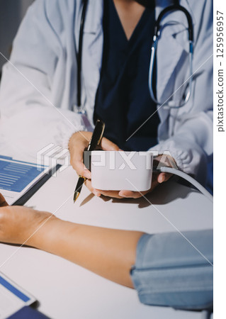 Nurse measuring blood pressure of elderly woman at table, closeup. Assisting senior generation 125956957