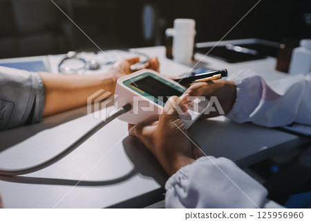 Nurse measuring blood pressure of elderly woman at table, closeup. Assisting senior generation Nurse measuring blood pressure of elderly woman at table, closeup. Assisting senior generation 125956960