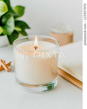 Serene candle on minimalist desk with journal and greenery, creating calming atmosphere 125957970