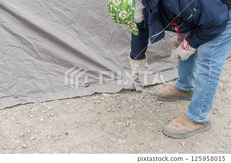 [Auto camping on the Nakatsugawa riverbed, removing the pegs from the tent skirt and preparing to withdraw] 125958015