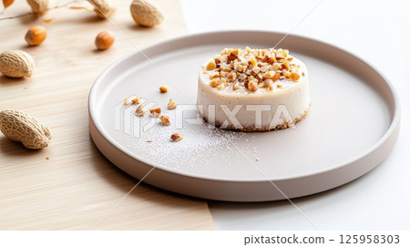 Delicate almond pastry garnished with pili nuts and caramel on a ceramic plate 125958303