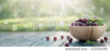 Ripe maqui berries nestled with mint leaves in weathered wooden bowl, highlighting superfruit against soft wooden surface and out-of-focus natural backdrop Ripe maqui berries nestled with mint leaves in weathered wooden bowl, highlighting superfruit against soft wooden surface and out-of-focus natural backdrop 125958348