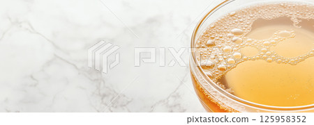 Nutrient-dense bone broth pouring into glass cup, resting on marble countertop, highlighting healing properties for wellness-focused consumers and biohacking enthusiasts 125958352