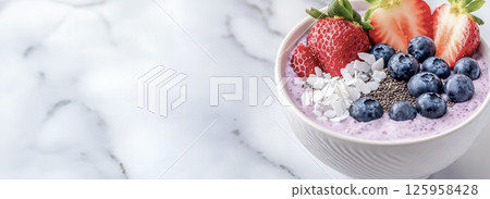 Colorful smoothie bowl garnished with strawberries, blueberries, coconut flakes, chia seeds on marble surface, representing nutritious breakfast trend Colorful smoothie bowl garnished with strawberries, blueberries, coconut flakes, chia seeds on marble surface, representing nutritious breakfast trend 125958428