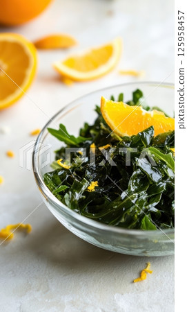 wakame salad, arugula, and orange wedges arranged artfully in a small, handcrafted glass bowl. wakame salad, arugula, and orange wedges arranged artfully in a small, handcrafted glass bowl. 125958457