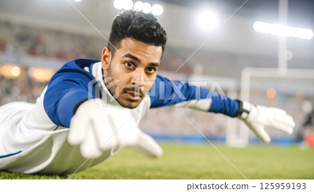 A soccer player is on the ground, stretching out his arm 125959193